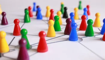 A strategic arrangement of colorful pawns connected on a game board, symbolizing networking and teamwork.